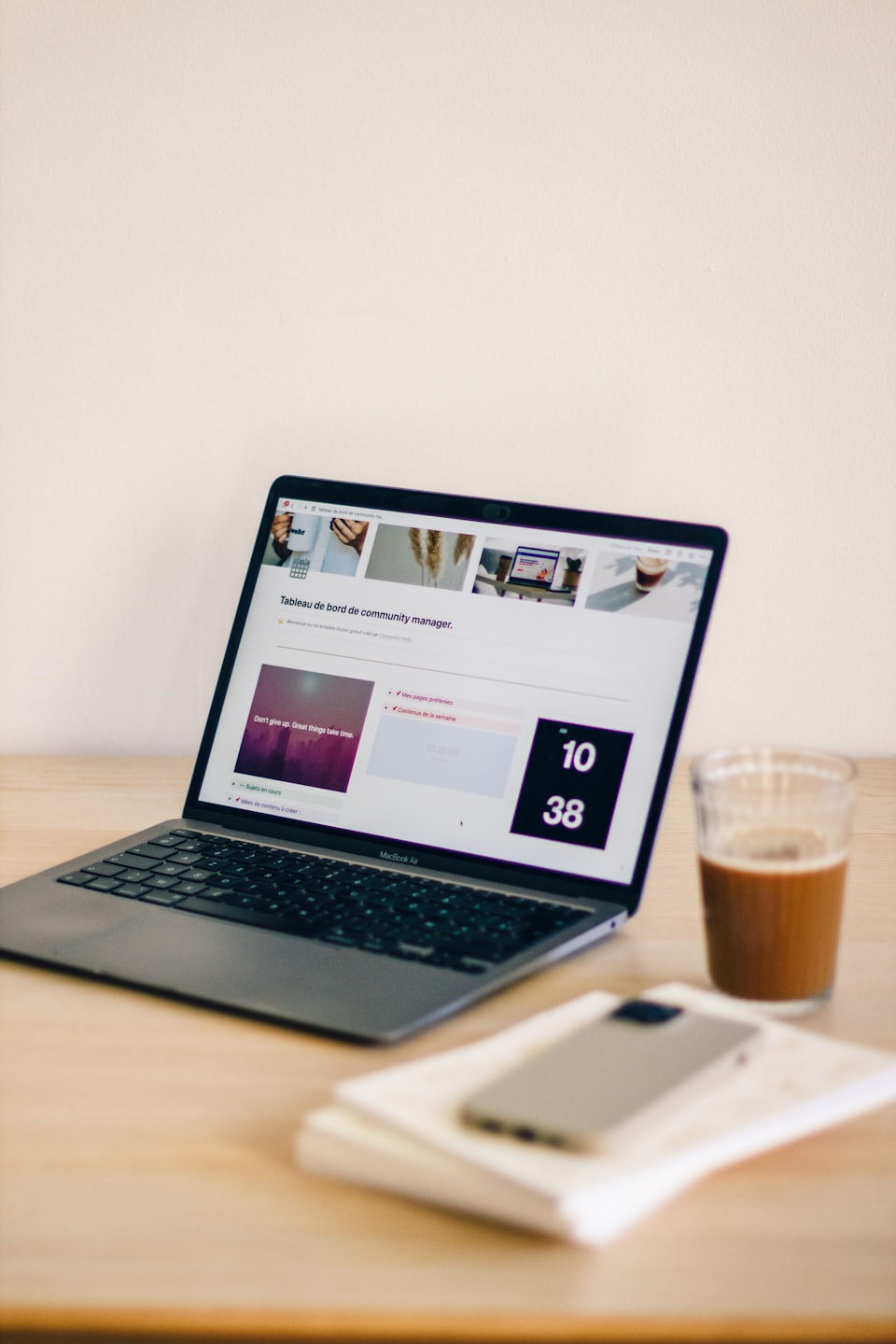 Laptop displaying dashboard on a wooden desk with iced coffee.