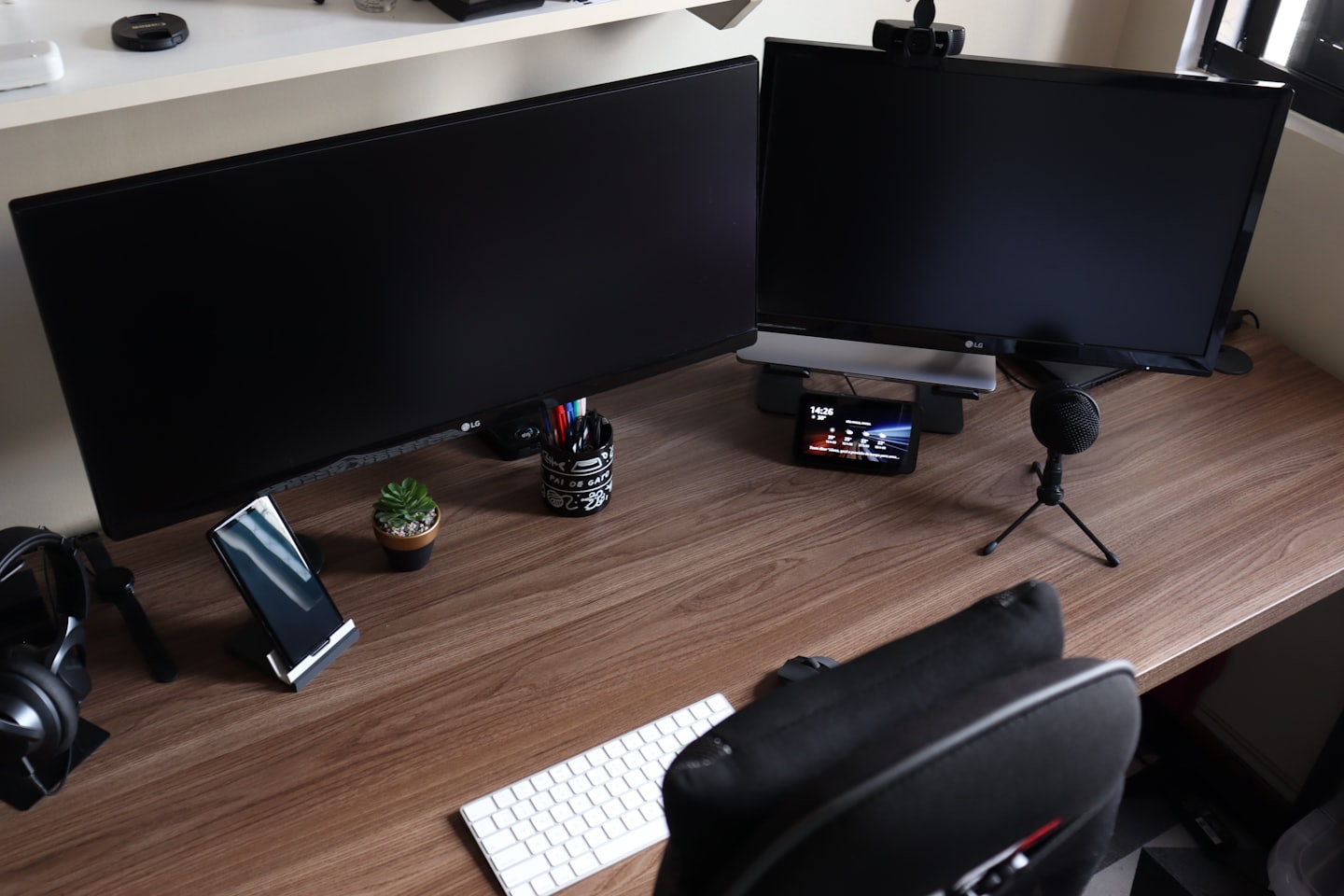 Clean desk with computers, keyboard, headphones, and succulent.